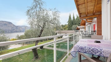 Un balcone con vista su un lago, un tavolo con tovaglia e un soffitto in legno.