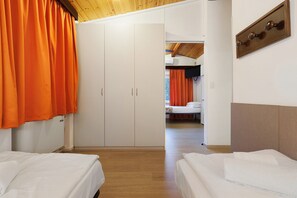 Une chambre d’hôtel avec un placard, deux lits et une vue sur une autre chambre.