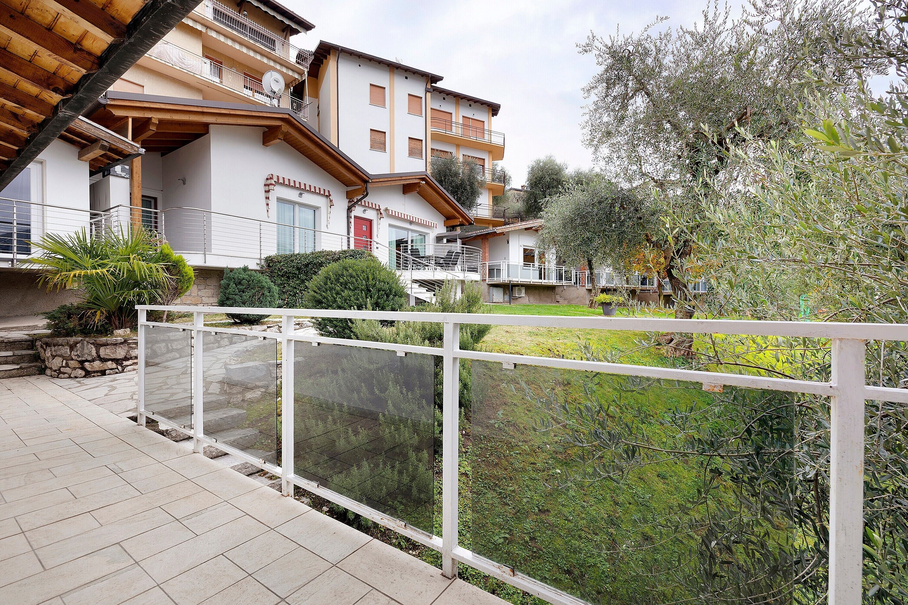 A residential building with a balcony, a stone wall, and a garden area.