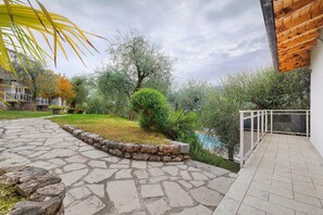 Un chemin de pierres mène à une terrasse en bois d’où l’on peut admirer un jardin et une étendue d’eau.