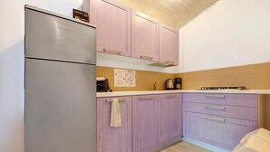 Eine Küche mit Kühlschrank, Schränken, einer Arbeitsplatte und einer Kaffeemaschine.