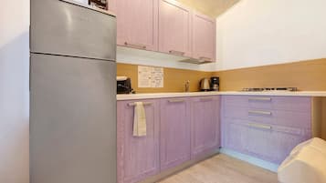Eine Küche mit Kühlschrank, Schränken, einer Arbeitsplatte und einer Kaffeemaschine.
