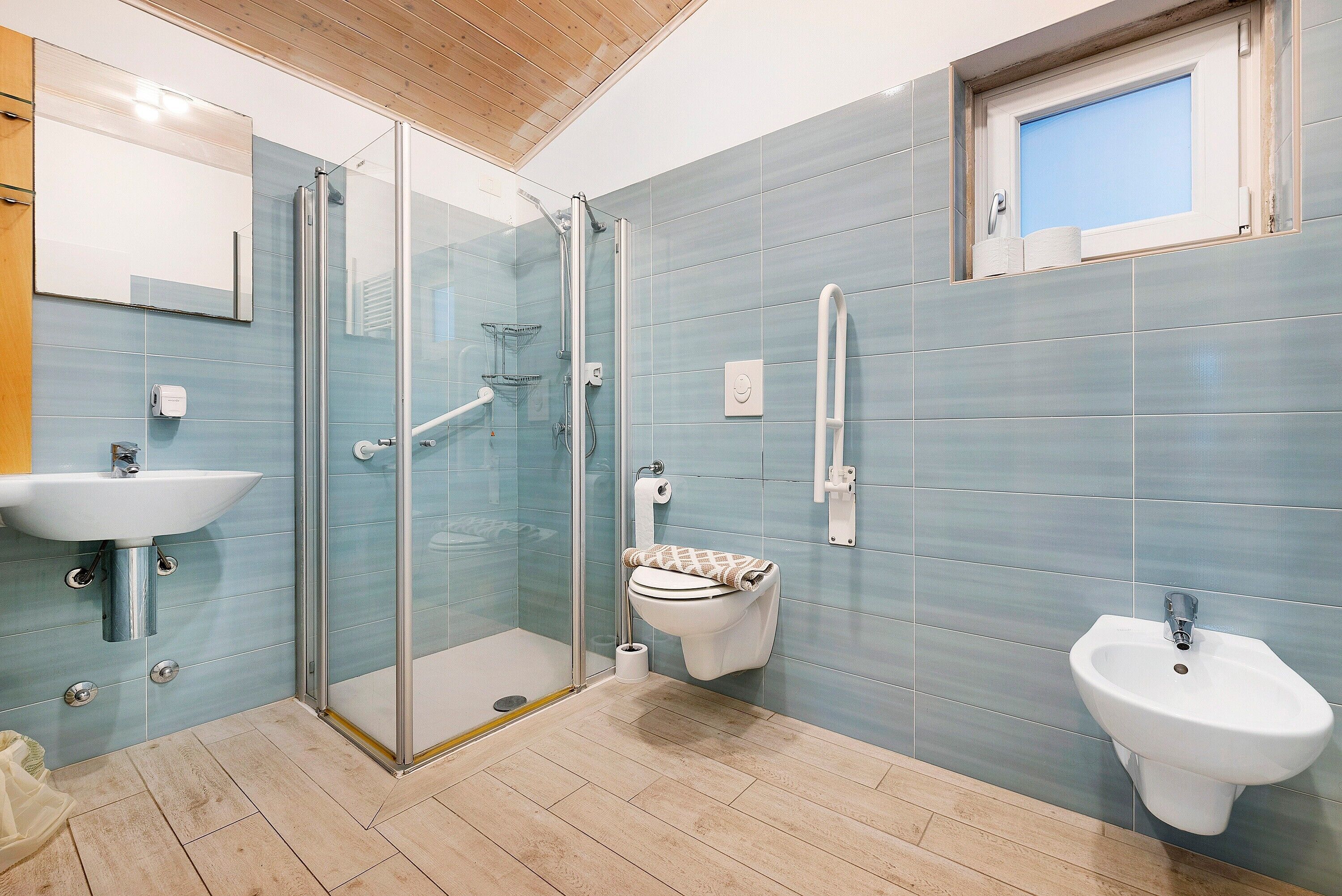 Ein modernes Badezimmer mit Duschkabine aus Glas, Toilette, Bidet und Waschbecken.