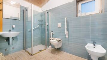 Ein modernes Badezimmer mit Duschkabine aus Glas, Toilette, Bidet und Waschbecken.