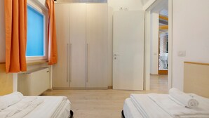 Ein Hotelzimmer mit zwei Betten, einem Kleiderschrank, einem Heizkörper und einer Klimaanlage.