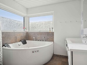 Une salle de bain moderne avec une baignoire sur pieds, un lavabo séparé et une fenêtre offrant une vue sur les montagnes.