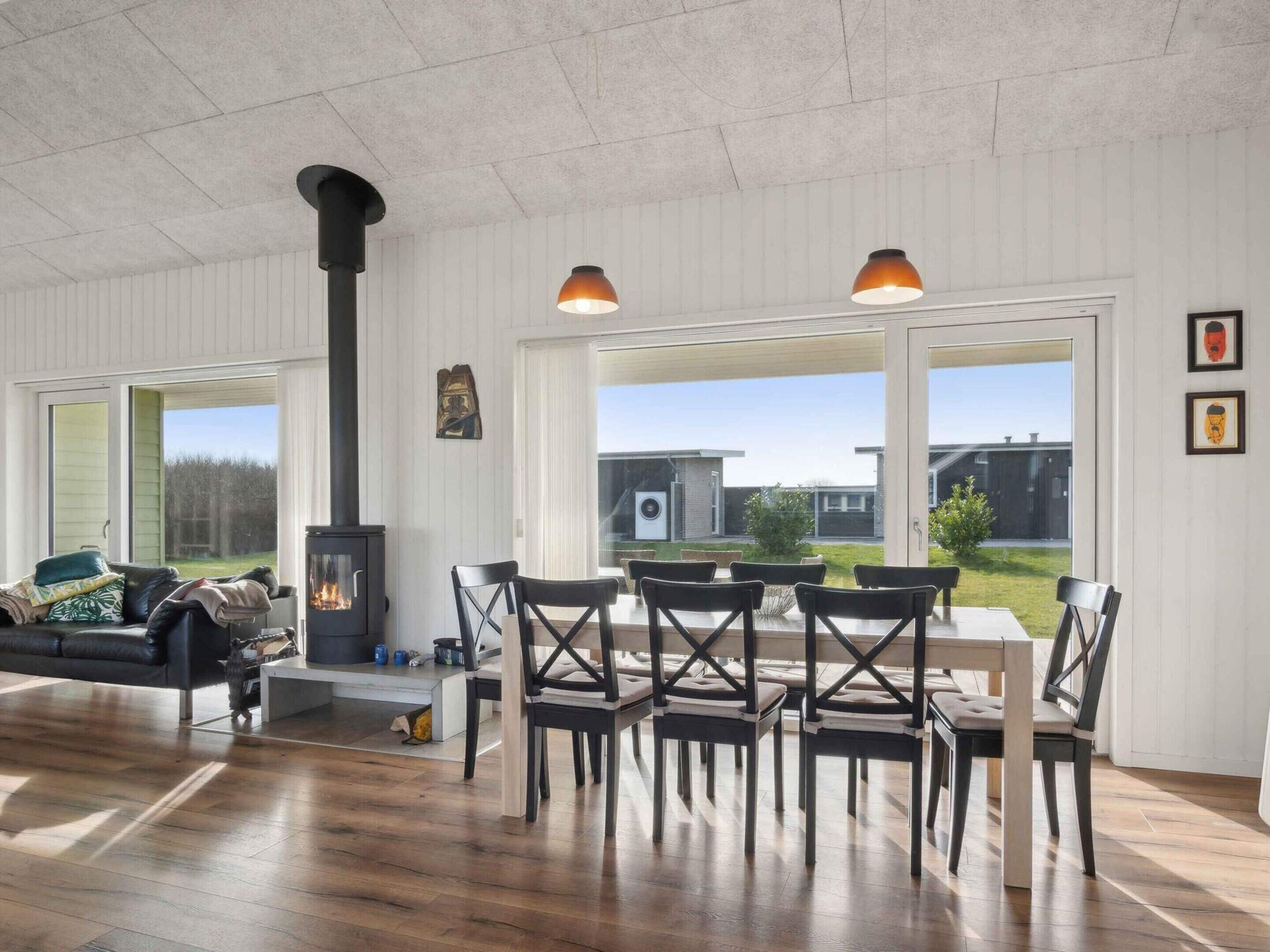 Een moderne woonkamer met een open haard, houten vloeren en een eethoek met stoelen en een tafel.