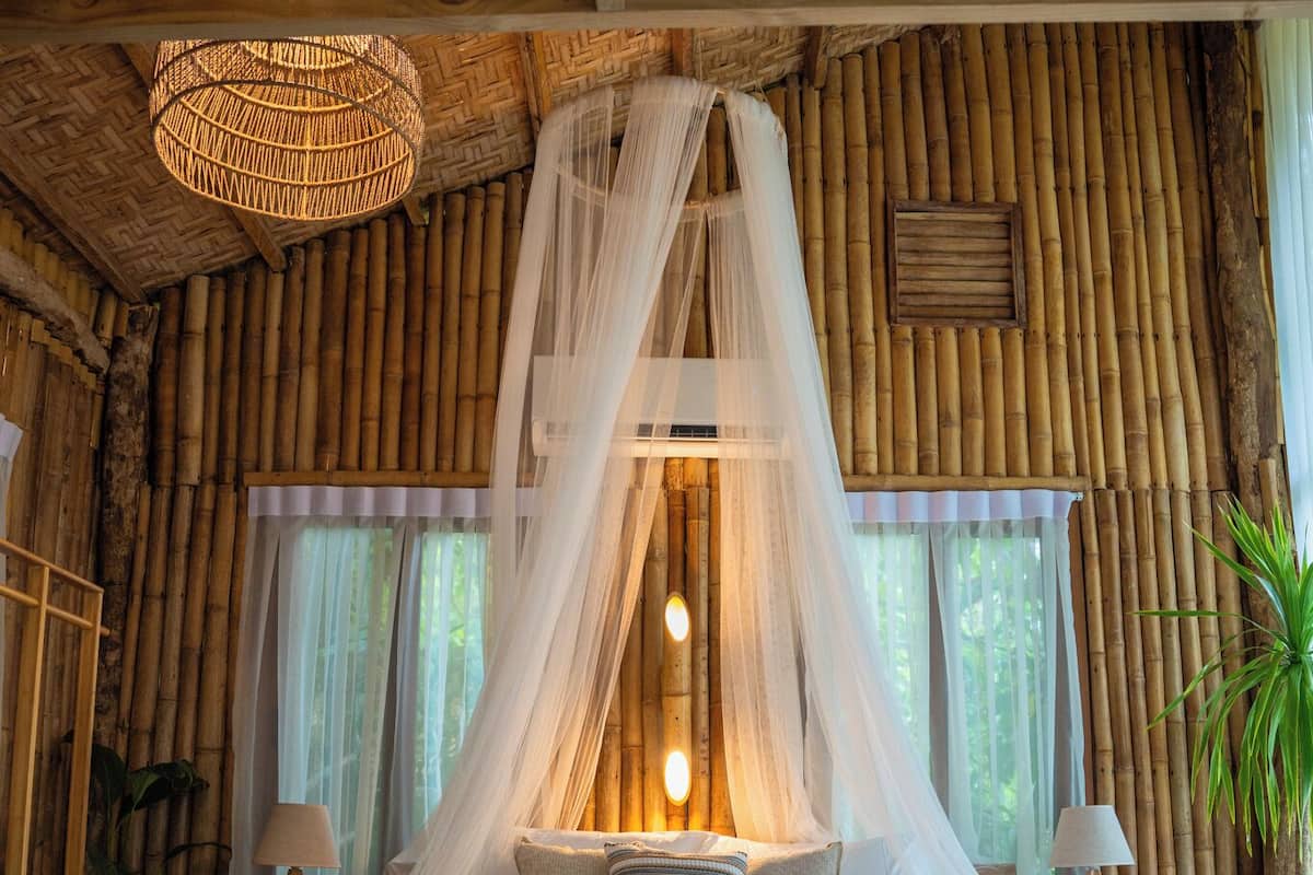 Una habitación con cama, lámpara colgante y paredes de bambú.