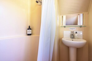 A bathroom with a bathtub, a white sink, and a mirror above the sink.