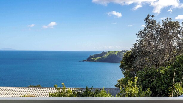 Une vue côtière avec un ciel dégagé, une étendue d’eau et une masse terrestre lointaine.