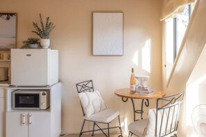 A compact kitchen with a microwave, a refrigerator, and a small dining area with a table and chairs.