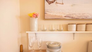 Un comptoir de cuisine orné d’un vase blanc rempli de fleurs, d’un ensemble de verres transparents et d’une pile d’assiettes.