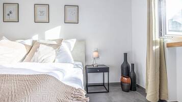 Una camera da letto ordinata con un letto, un comodino, una lampada e vasi decorativi.