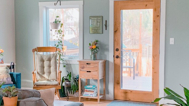 Una sala de estar acogedora con una silla de madera, una mesita y una estantería.