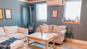 Una sala de estar acogedora con un sofá, una mesa de centro, una chimenea y una ventana con vistas.