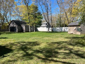 A fenced yard with a wooden building, a garage, and a shed.