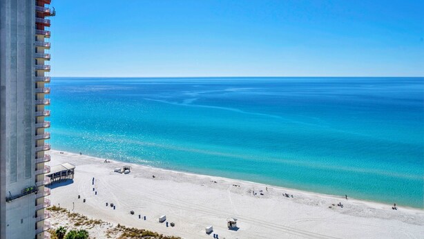 A beach with a clear view of the ocean, a building with multiple balconies, and a sandy beach area with some structures. -    🌊Gulf and Pool Views-Pool-Fab Amenities-Shores of Panama 1711🌊 (Panama City Beach)