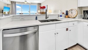 A modern kitchen with a dishwasher, a sink, and a clock. - 🌊Gulf and Pool Views-Pool-Fab Amenities-Shores of Panama 1711🌊 (Panama City Beach)