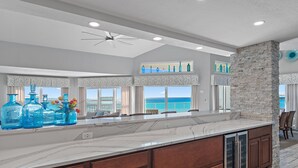 A spacious kitchen with a large island, stone accent wall, and large windows offering a view of the ocean. - ☀️Stunning Gulf Views-Pet Friendly-Cabana Club C408- Sugar Sand Shores☀️ (Destin)