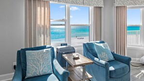 A room with two blue armchairs, a small wooden table, and a view of the beach through large windows. - ☀️Stunning Gulf Views-Pet Friendly-Cabana Club C408- Sugar Sand Shores☀️ (Destin)