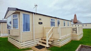 A mobile home with a small porch, a staircase, and a satellite dish. - Caravan by the sea with direct access to the beach.  Pet friendly! (Barton on Sea)