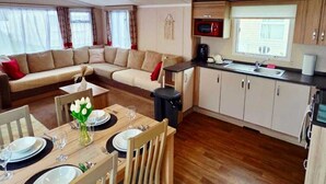 A compact living space with a dining area, kitchenette, and a sofa.