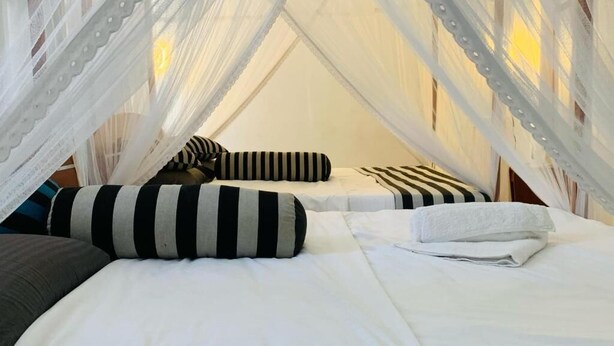 Una habitación con dos camas, cada una con ropa blanca y almohadas a rayas.