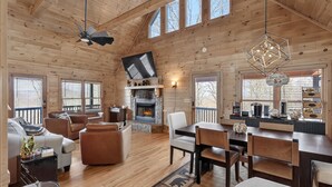 L’intérieur d’un chalet en bois comprend une cheminée, un coin salon, une table à manger et un espace cuisine.
