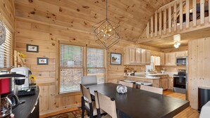L’intérieur d’un chalet en bois comprend un coin repas, une cuisine et un escalier.