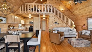 L'intérieur d'un chalet en bois comprend un coin repas, un canapé et un escalier.