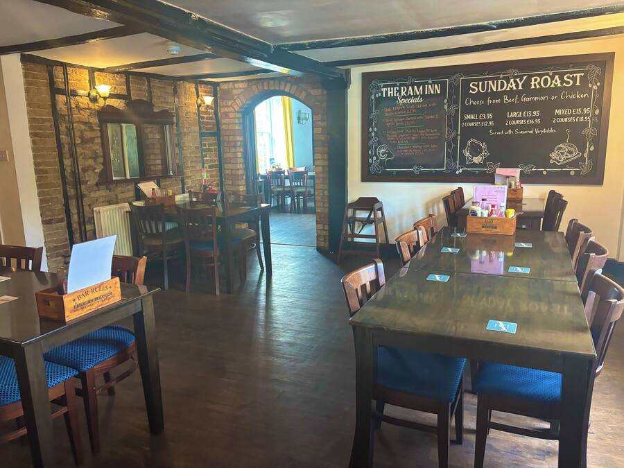 A restaurant interior with a long dining table, chairs, and a chalkboard menu.