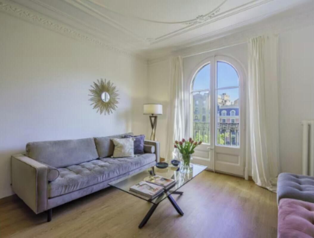 Ein Wohnzimmer mit einer Couch, einem Couchtisch und einem Fenster mit Vorhängen.