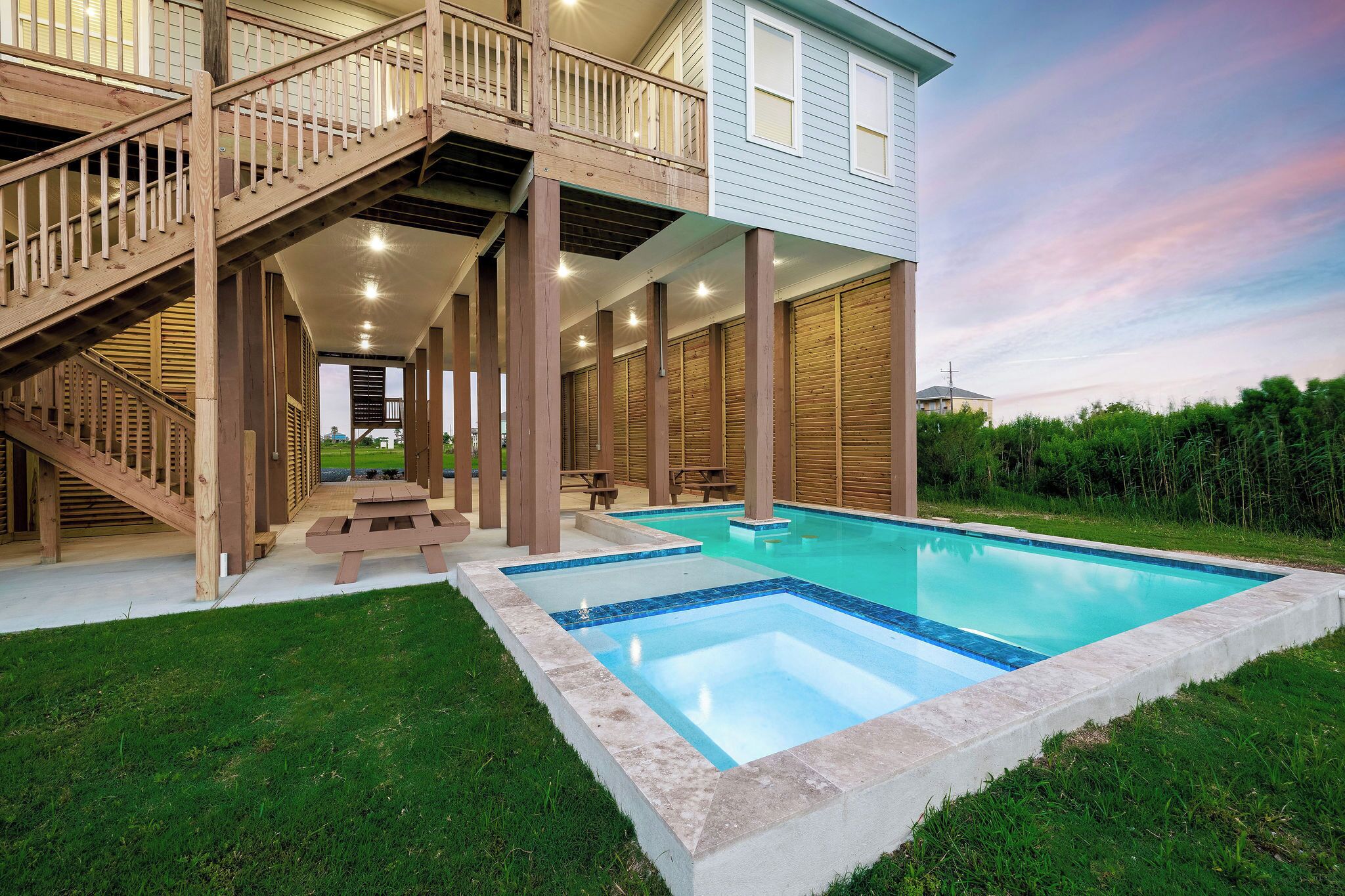 A two-story house with a wooden staircase, a covered patio area, and a swimming pool.