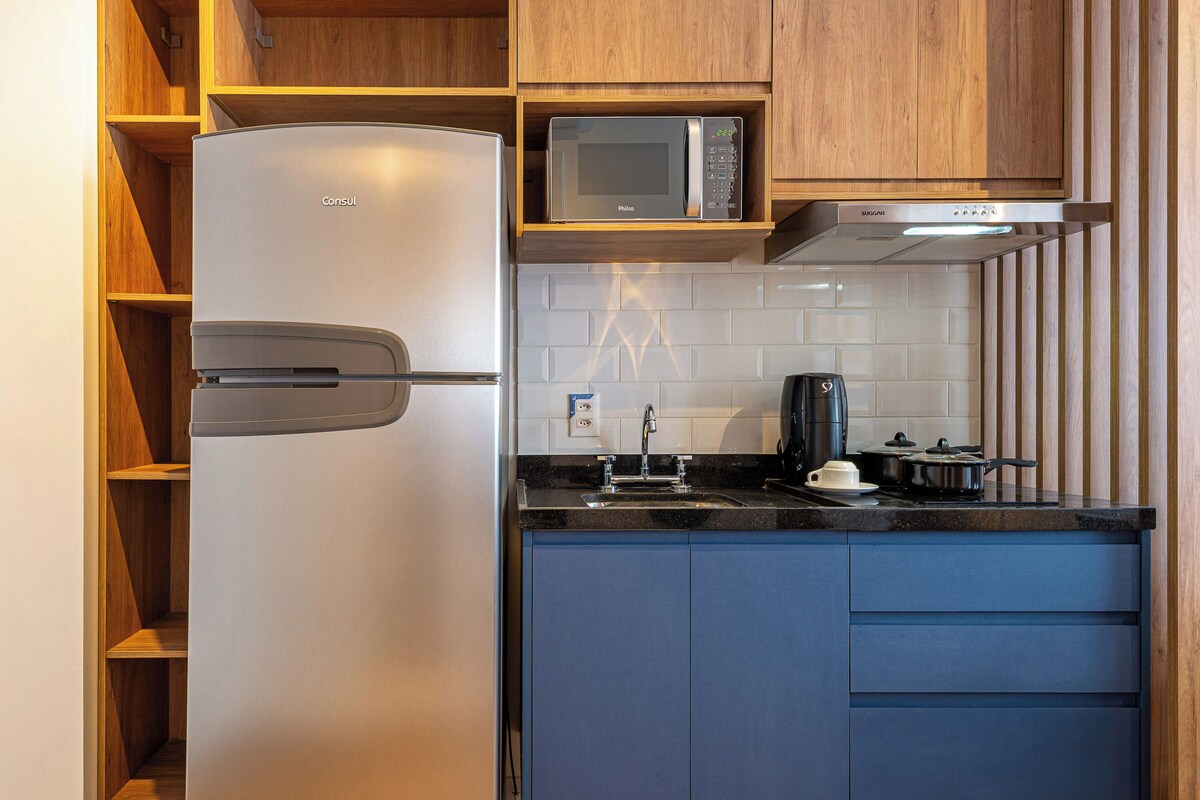 Cocina compacta con refrigerador, microondas, estufa y armarios azules.