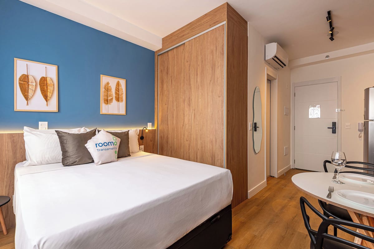 A hotel room with a bed, a round dining table with chairs, and a mirror.