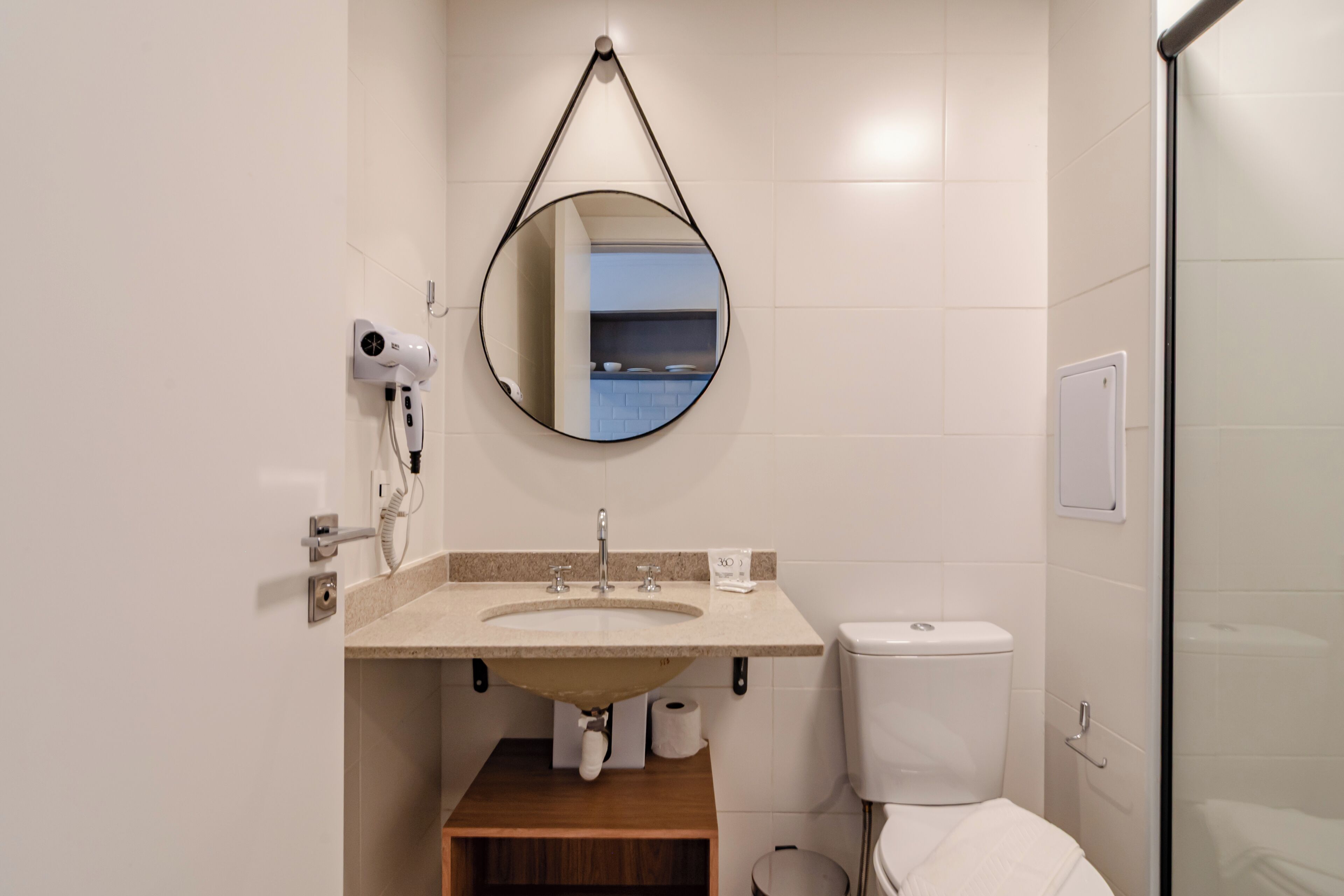 Un bagno con lavandino, specchio, WC e portasciugamani a parete.