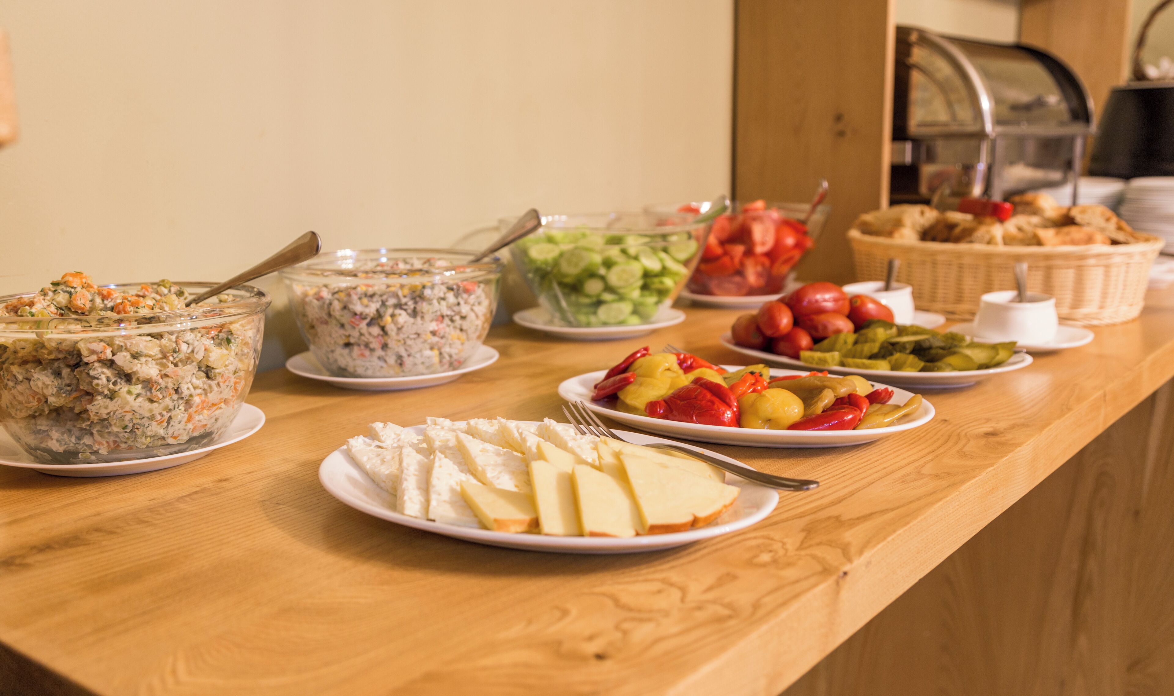 Una mesa de bufé con diversos alimentos, como ensaladas, frutas y queso.