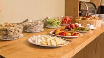 Una mesa de bufé con diversos alimentos, como ensaladas, frutas y queso.