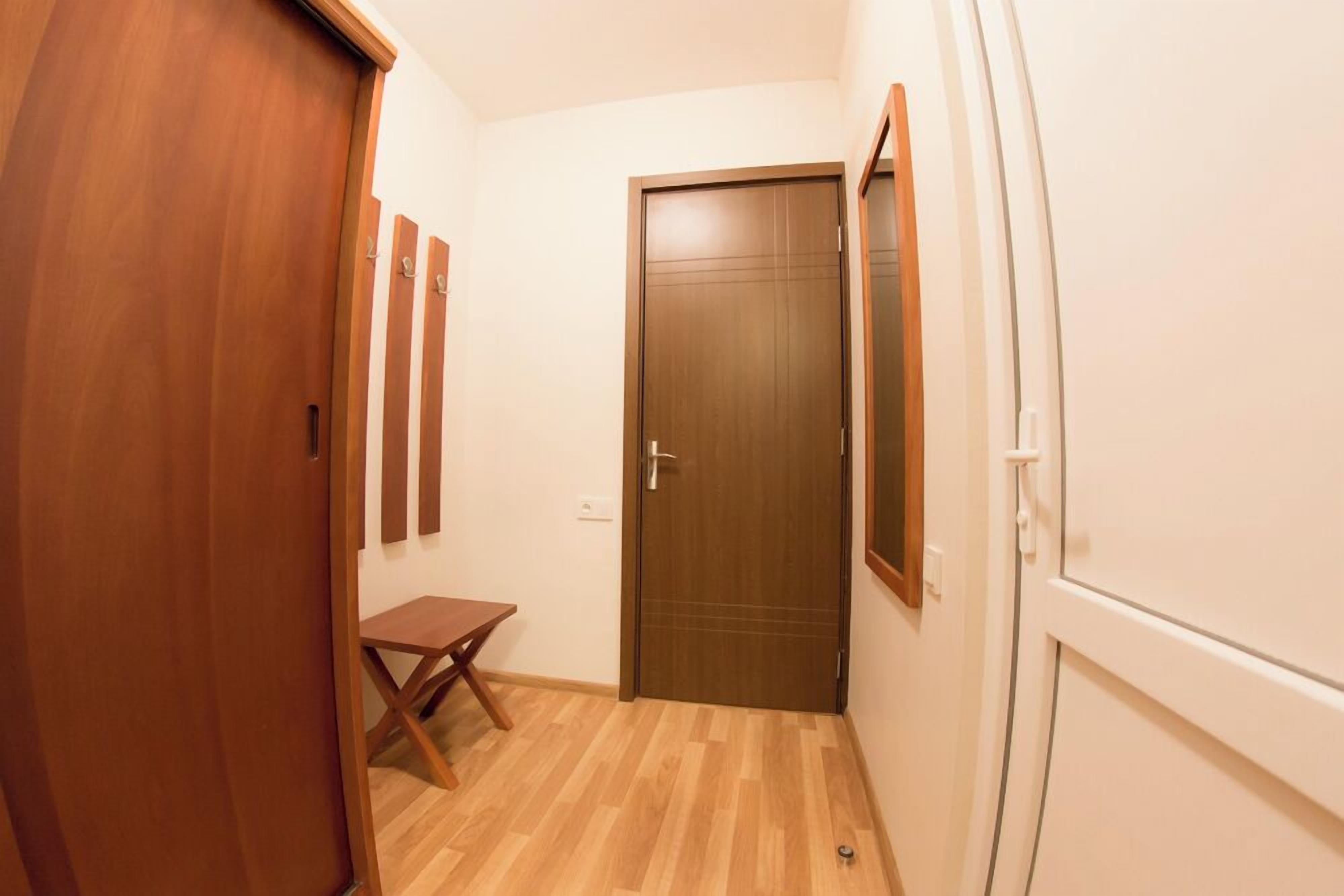 Ein Flur mit einer Holztür, einem kleinen Tisch und einem Spiegel an der Wand.