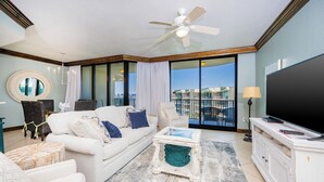 A spacious living room with a white sofa, a coffee table, and a television. - Phoenix on the Bay 1527 (Orange Beach)