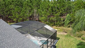 A modern house with a large glass-enclosed deck overlooking a swimming pool. - NEW - Free pool-/spa heat near Disney (Kissimmee)