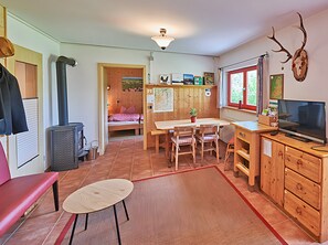 Una habitación compacta con una cama, una mesa de comedor con sillas, televisión y chimenea.