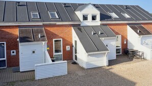 A row of white mobile homes with grey roofs, each featuring a small window and a door.