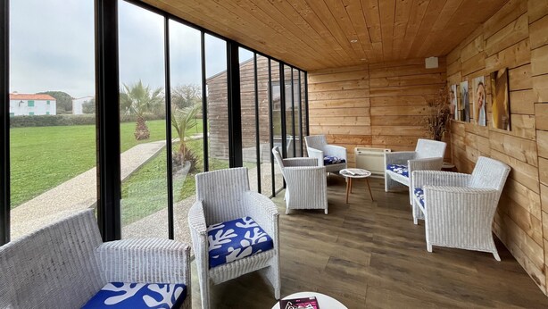 A modern room with large windows, wicker furniture, and a wooden ceiling. - THALACAP Ile de Ré (Ars-en-Ré)
