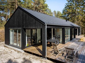 A modern cabin with a large deck, large windows, and a wooden exterior. - 5 Star Holiday Home in Nexo (Nexø)