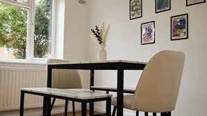 A dining area with a table and chairs, a vase with flowers, and wall art.