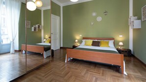 A bedroom with a wooden bed, two bedside tables with lamps, a large mirror, and green walls. - Casa Sacchi nei pressi di Porta Nuova by Wonderful Italy (Turin)