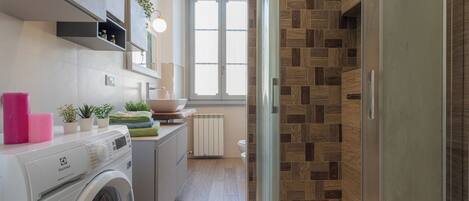 A modern kitchen with a washing machine, a sink, and a window.