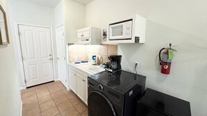 Cocina compacta con lavadora, microondas y cafetera.