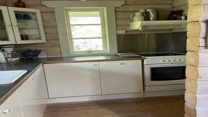 A compact kitchen with a stove, oven, and a window. - 4 Star Holiday Home in Ronne (Ronne)